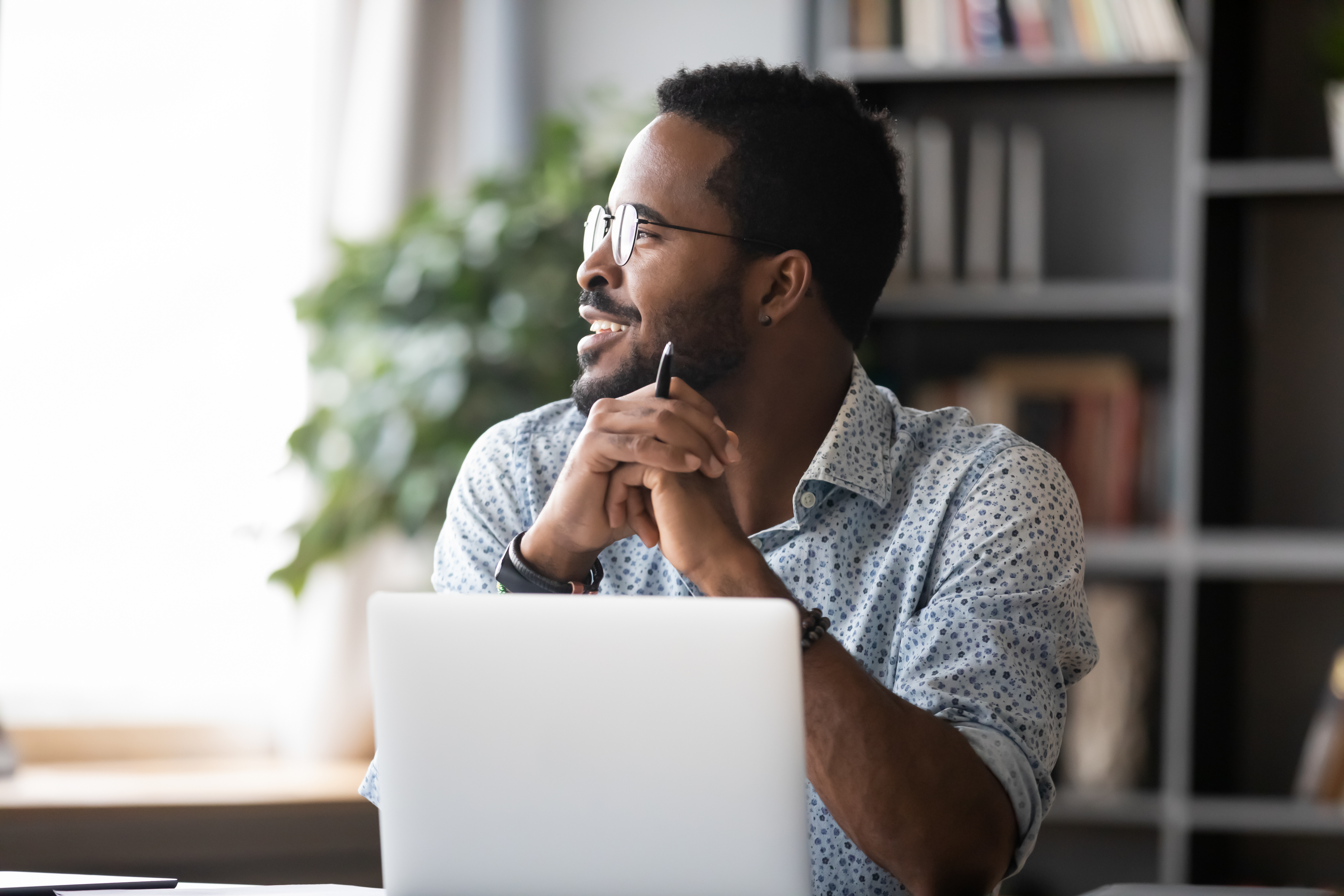 Black man with glasses smiling in front of laptop