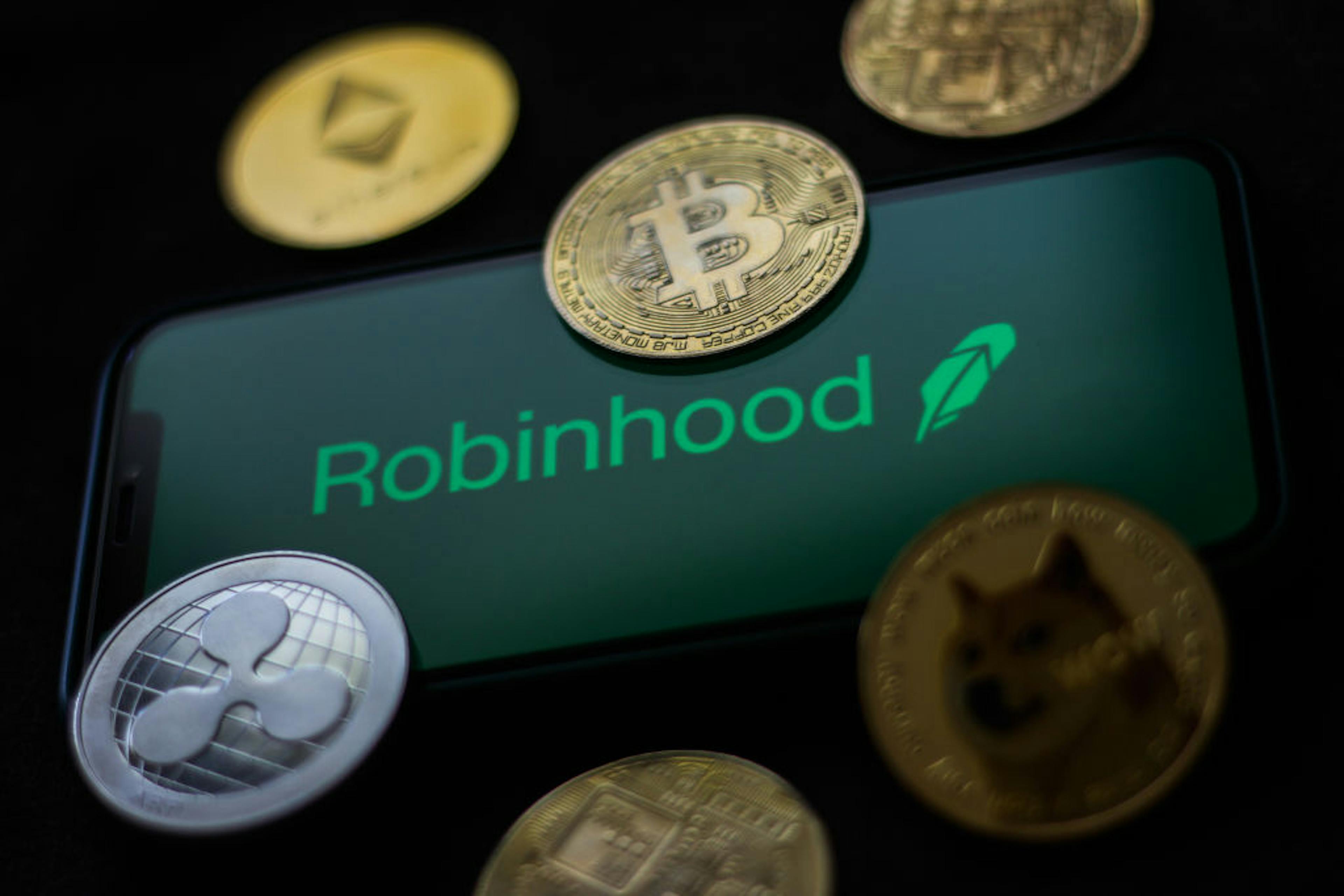 Robinhood logo displayed on a phone screen and representation of cryptocurrencies