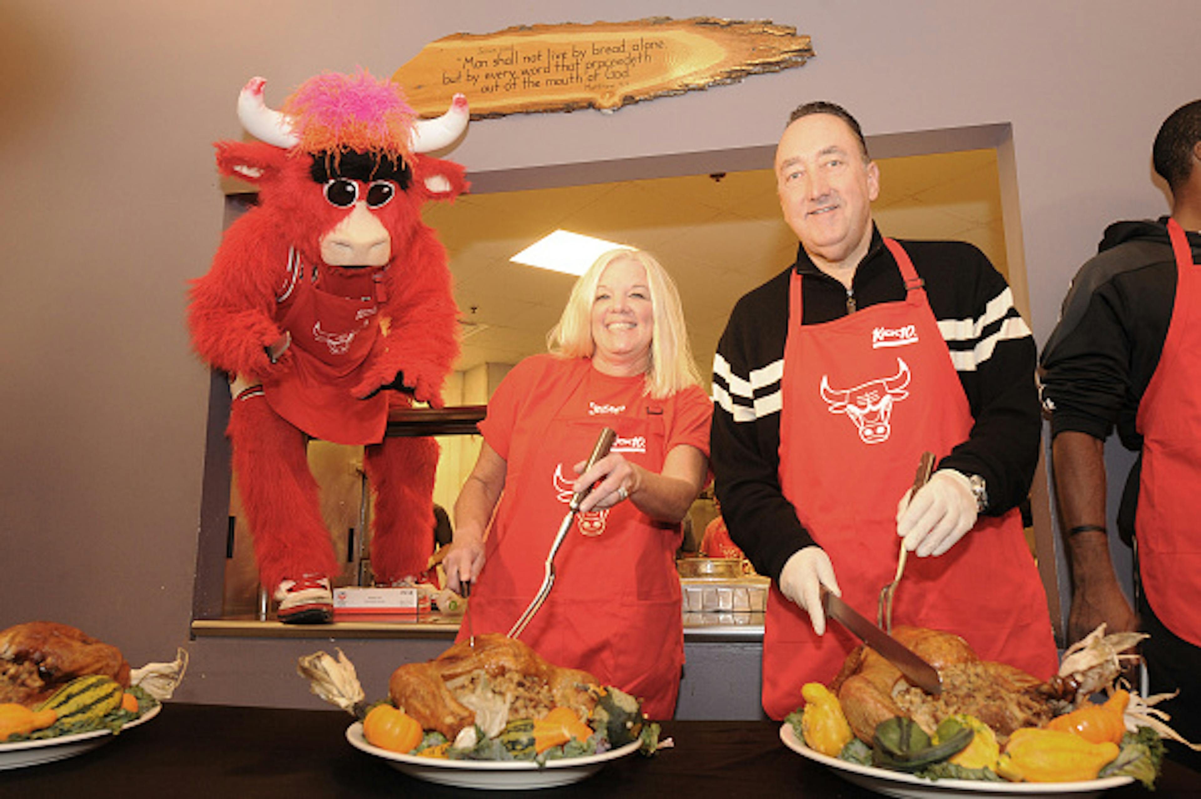 CHICAGO, IL - NOVEMBER 09: Chicago Bulls General Manager Gar Forman (R) and Chicago Bulls Charities Vice President Nancy Forman prepare to carve turkeys while mascot Benny the Bull observes during the team's 12th Annual Thanksgiving Dinner.