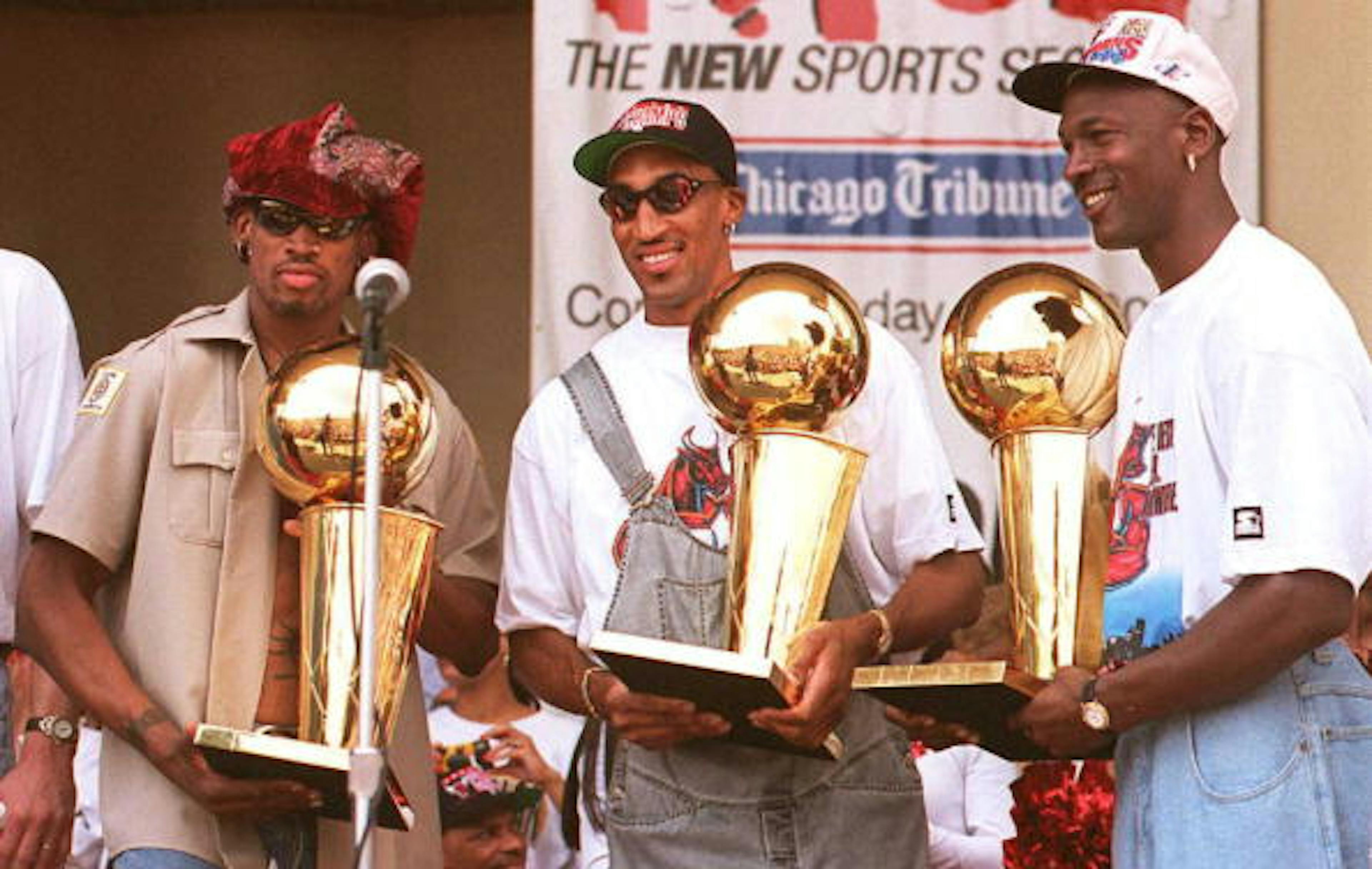 Chicago Bulls players Dennis Rodman (L), Scottie Pippen (C) and Michael Jordan (R) hold three of the team's four recent Larry O'Brien trophies 18 June at a rally for the team in Grant Park in Chicago. 