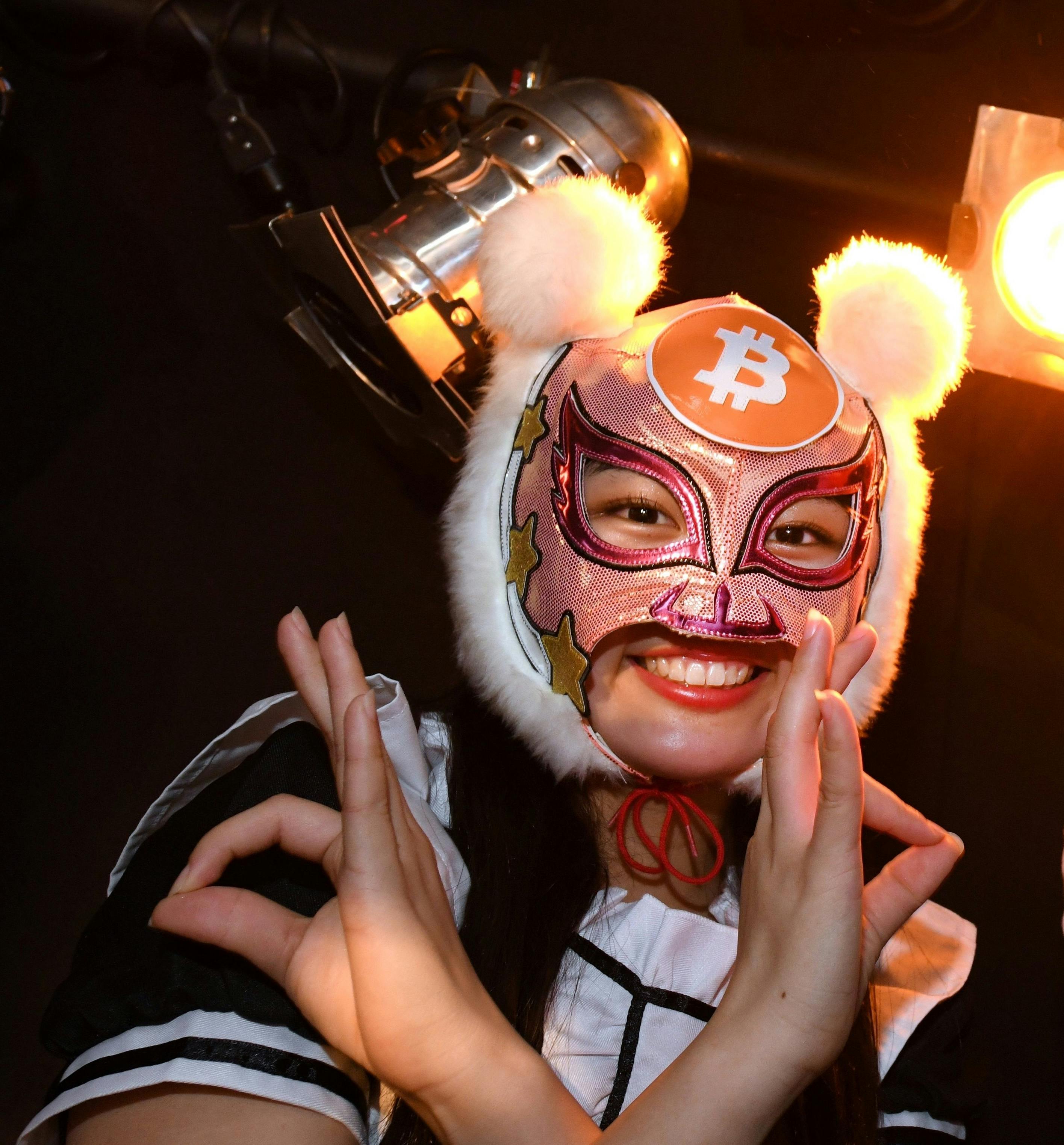 A member of idol group Kasotsuka Shojo (Virtual Currency Girls) wearing a bitcoin mask