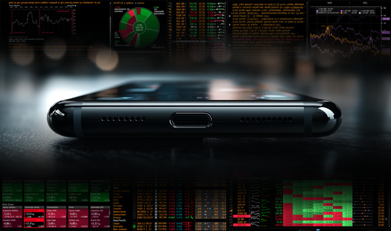 Bottom of a phone with desktop trading software in the background