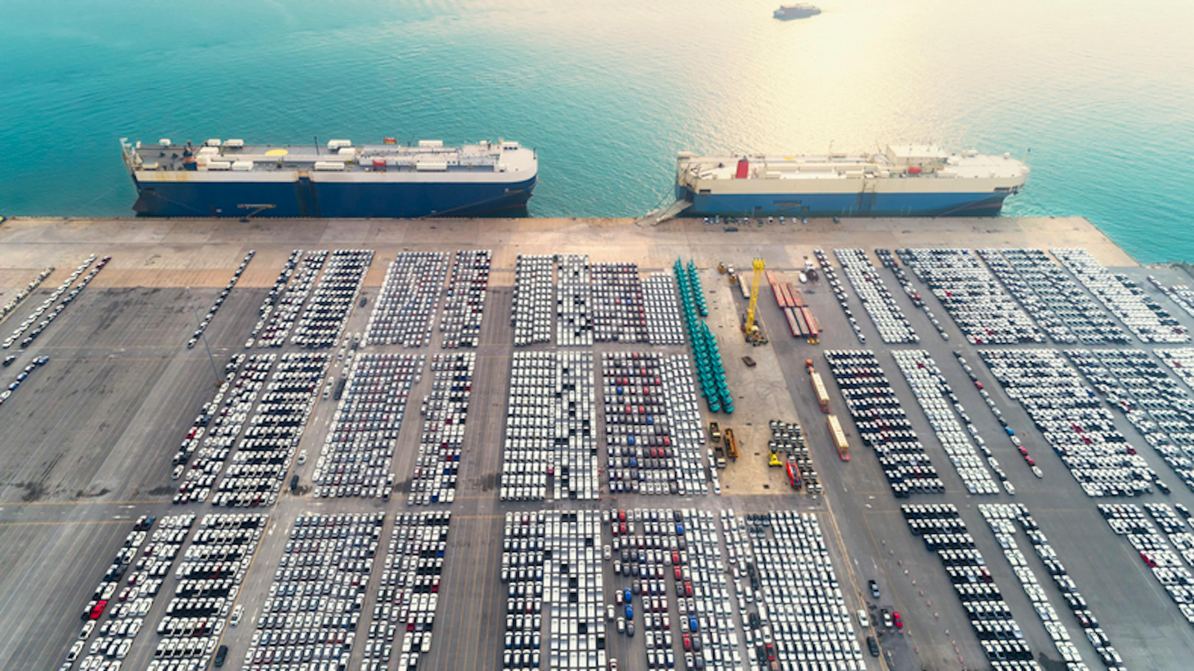 Aerial view Large RoRo (Roll on/off) carrier vessels convey cars and trucks at quayside into and out of the world market.