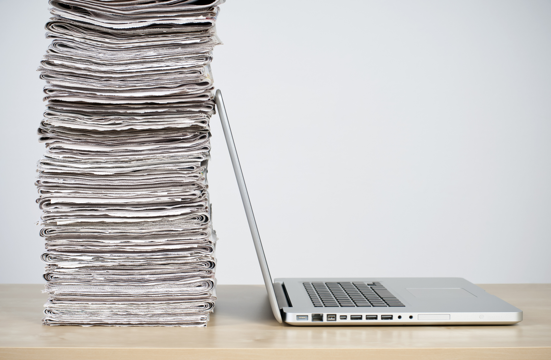 Newspapers stacked up against a laptop