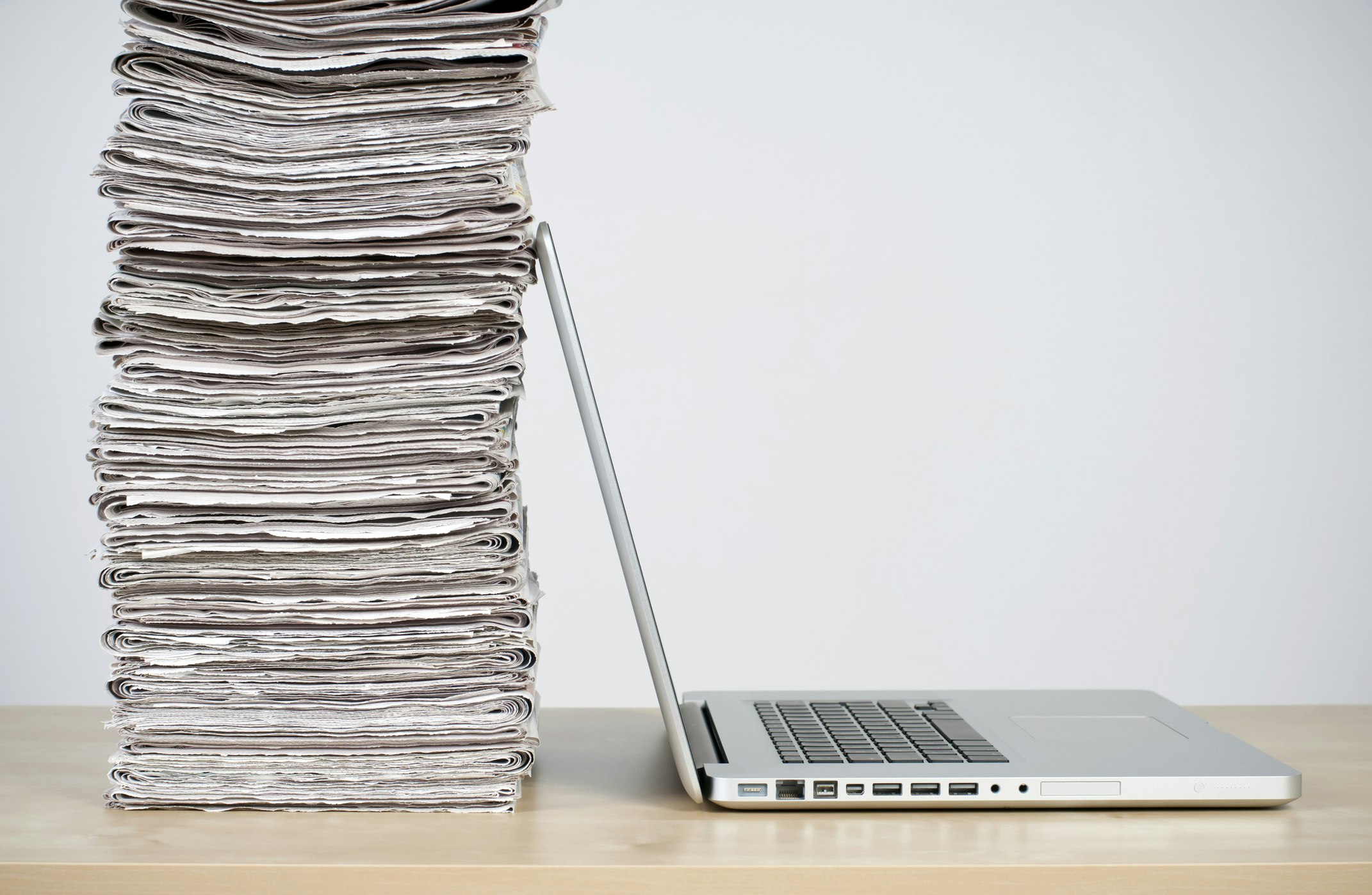 Newspapers stacked up against a laptop