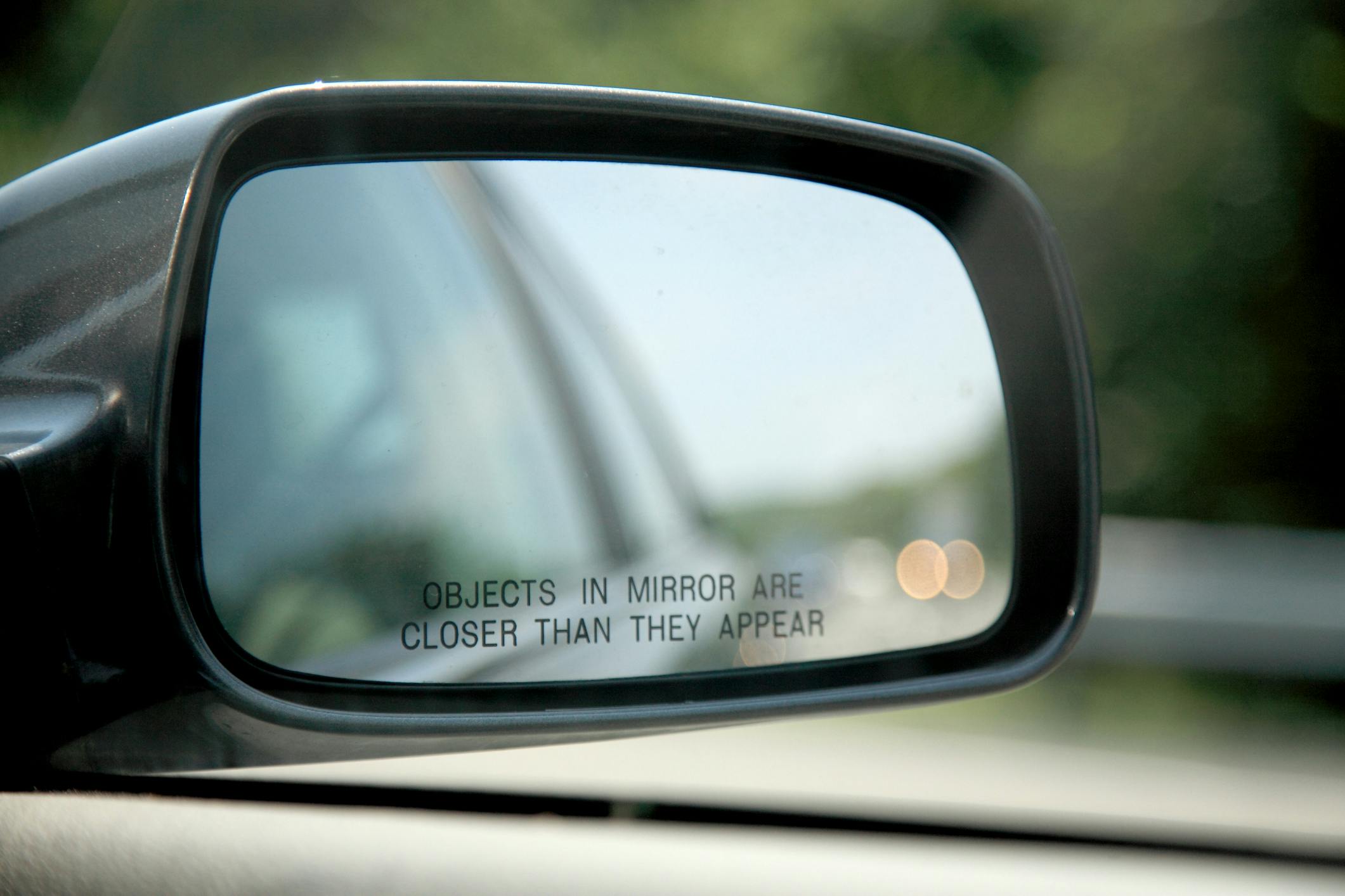 Close-up of car mirror objects are closer than they appear