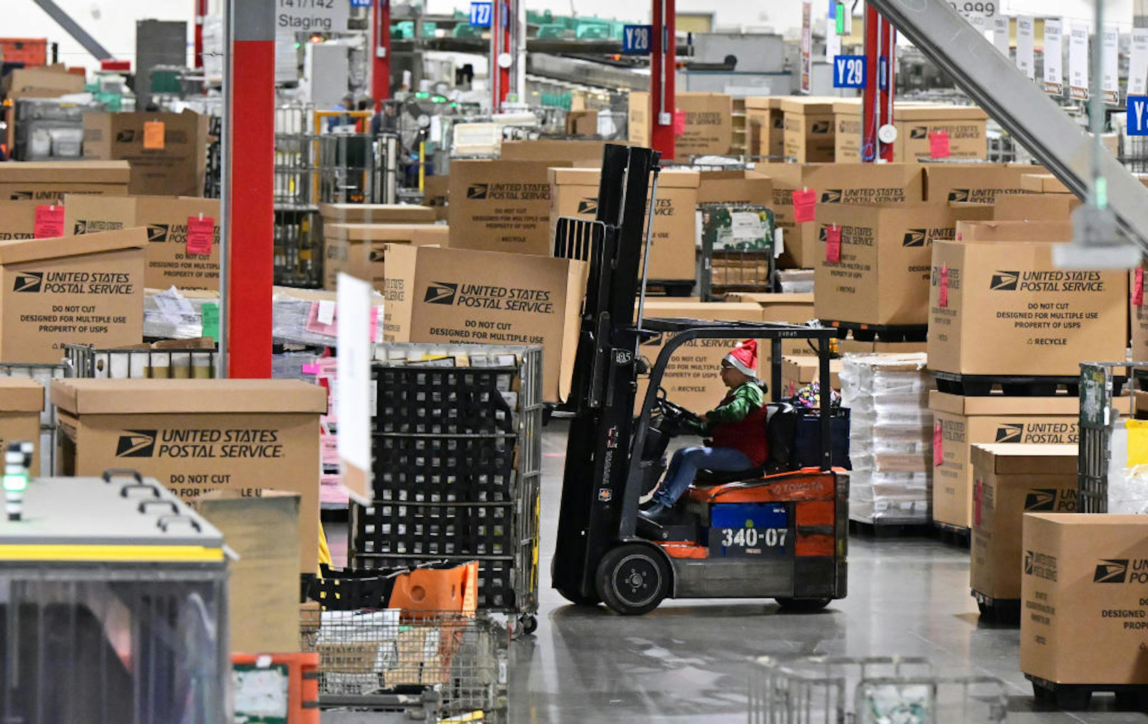USPS worker in a Santa hat operating a forklift 