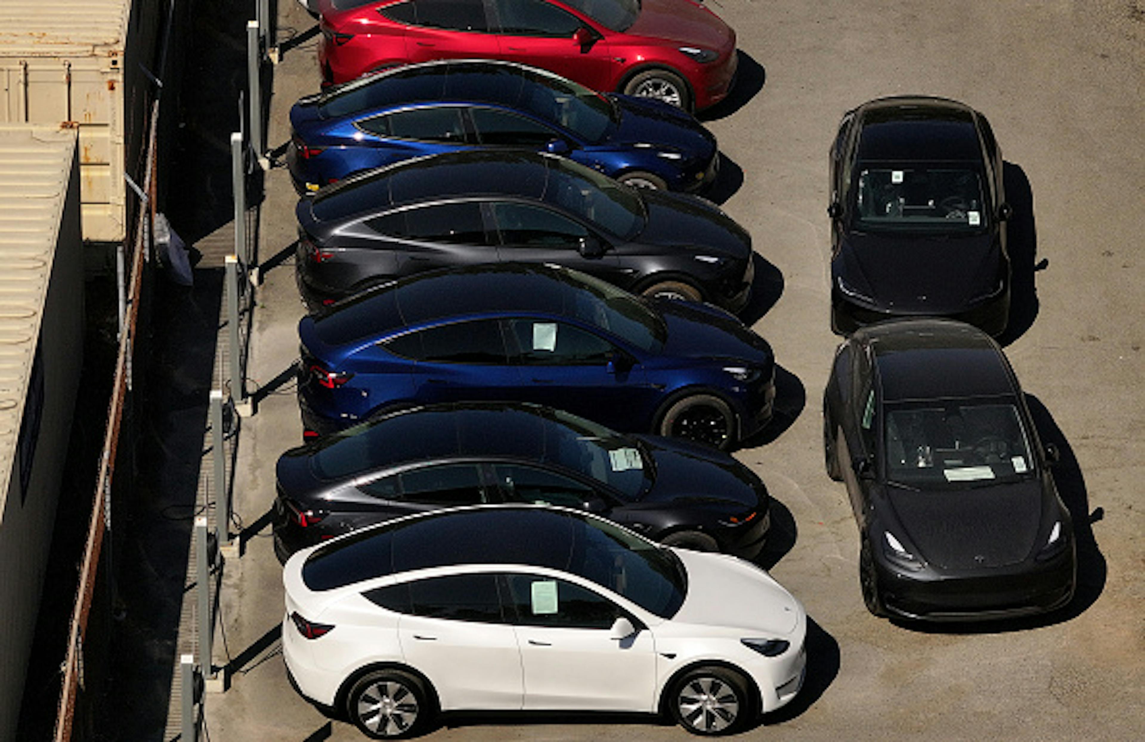 Tesla cars sit parked at a Tesla dealership