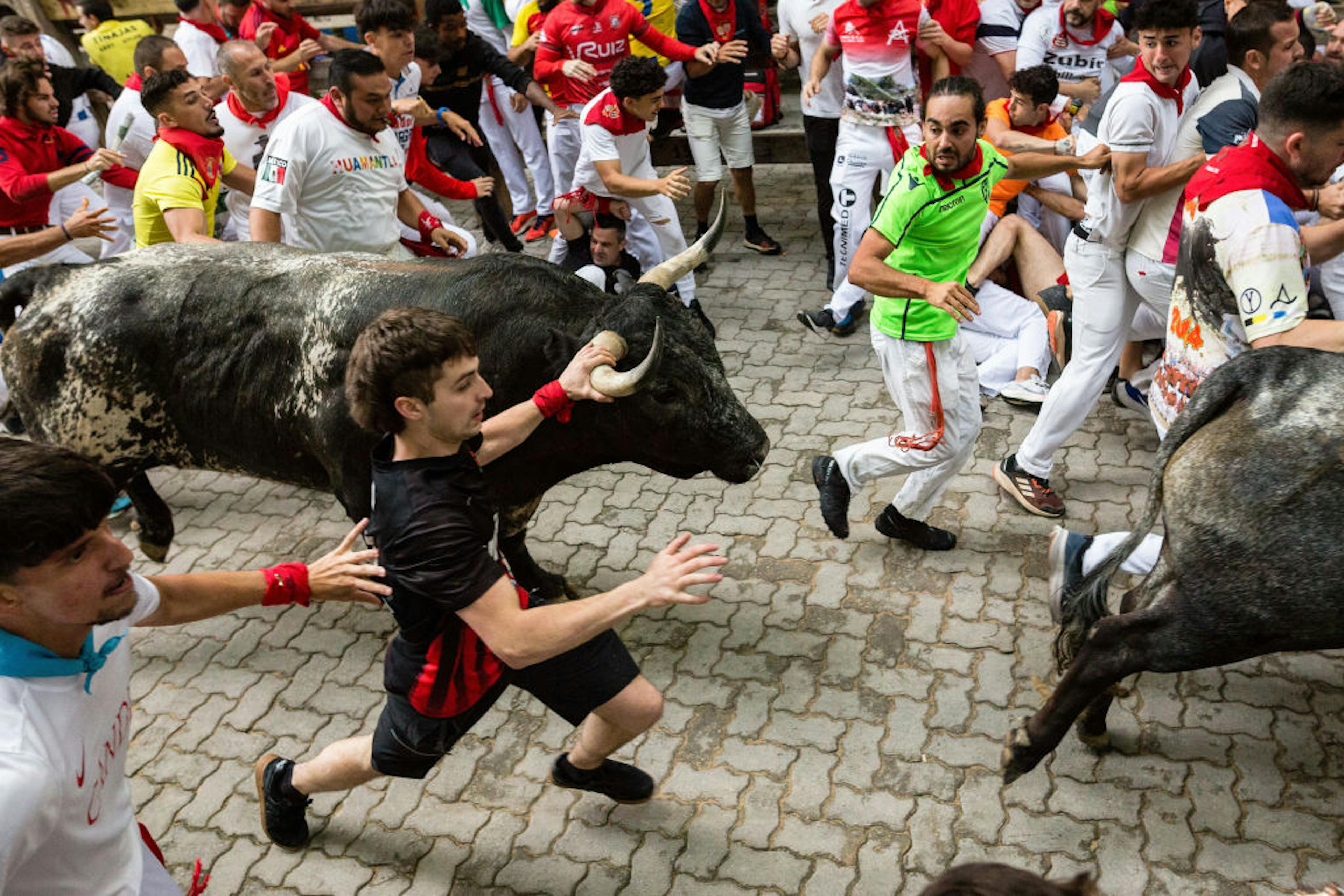Runners race through the streets of Pamplona, with some...