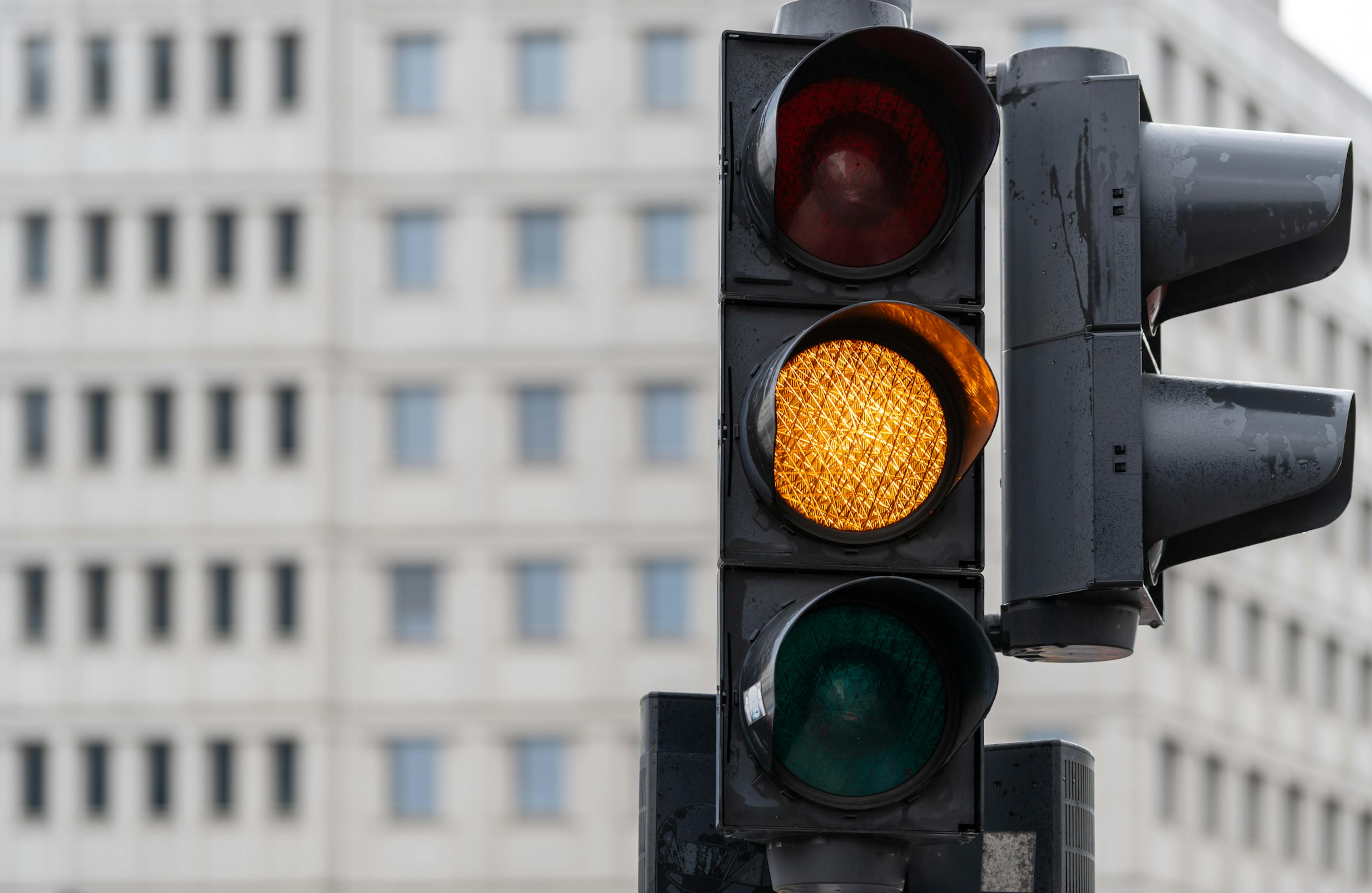 Yellow traffic light against an office building