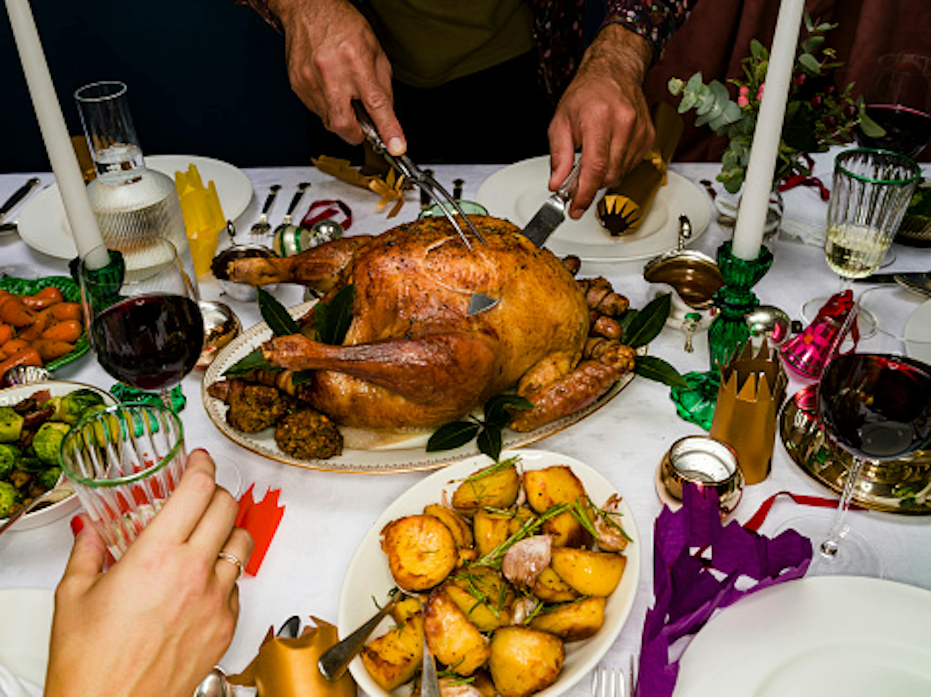 Man carving roasted Christmas turkey at dinner table