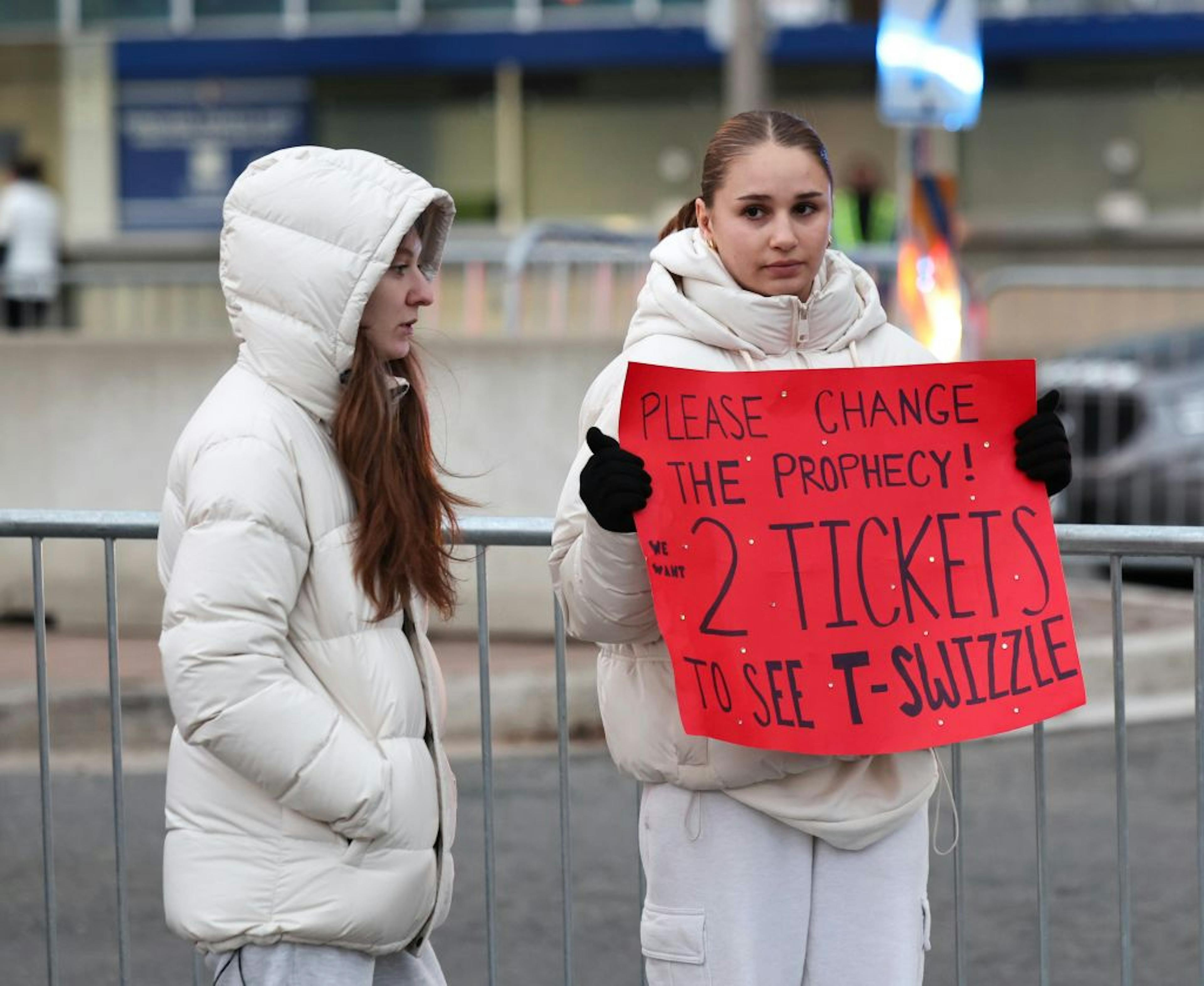 2 fans holding a sign for tickets at Taylor Swift show