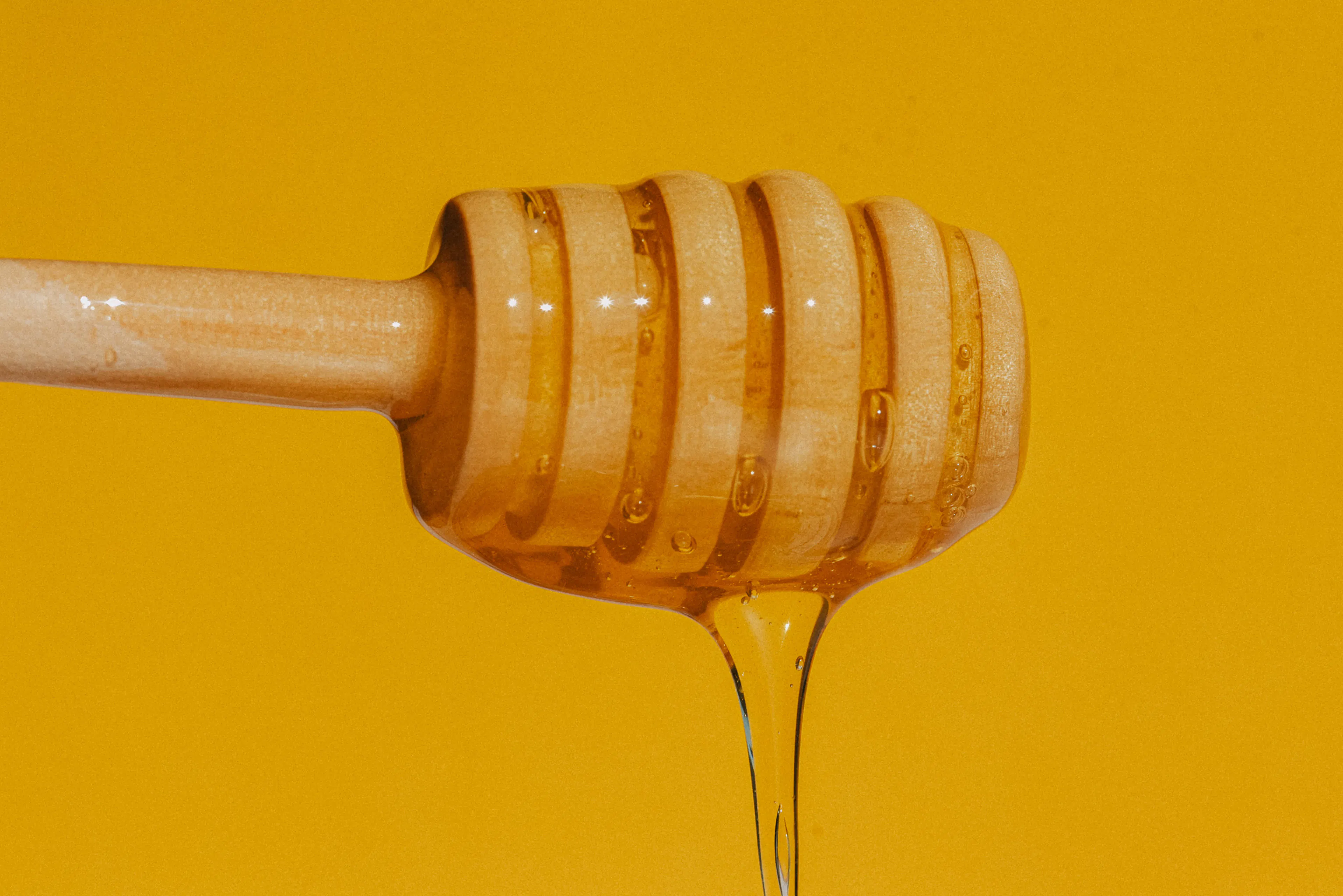 A honey dipper drizzles golden honey