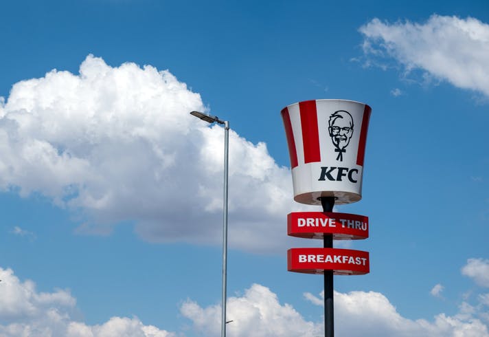 KFC sign. Fried chicken brand, bucket shape signage, blue sky with clouds. South Africa.
