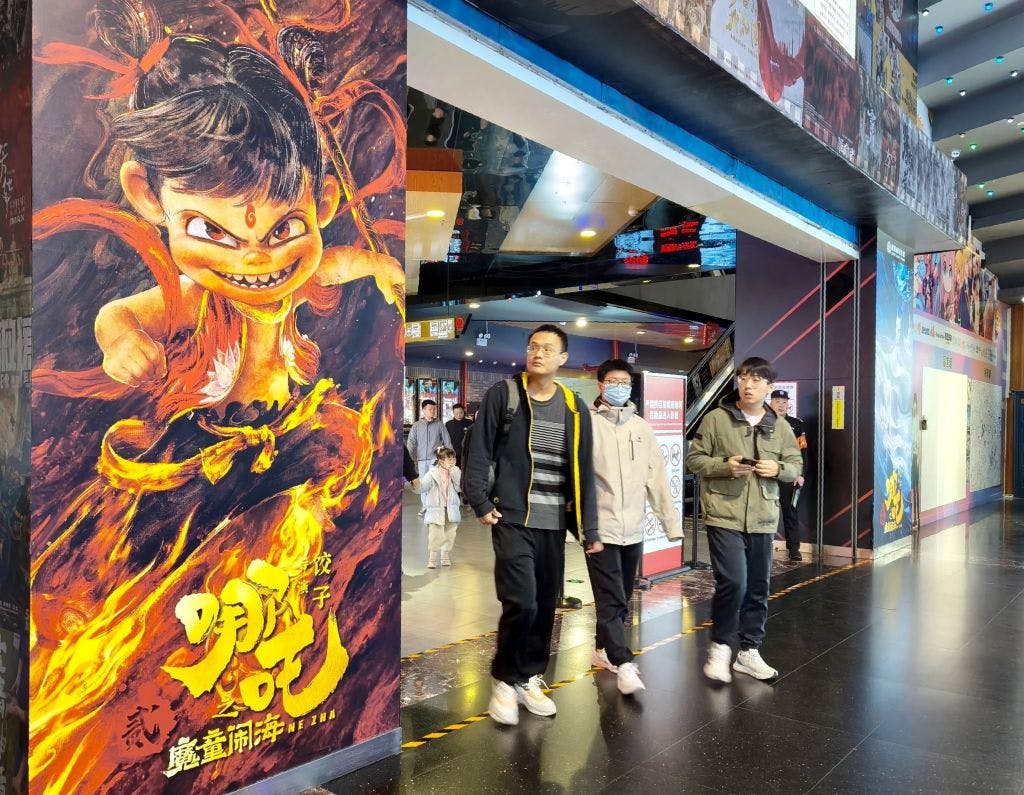 People walk past poster for Ne Zha 2 in Beijing cinema