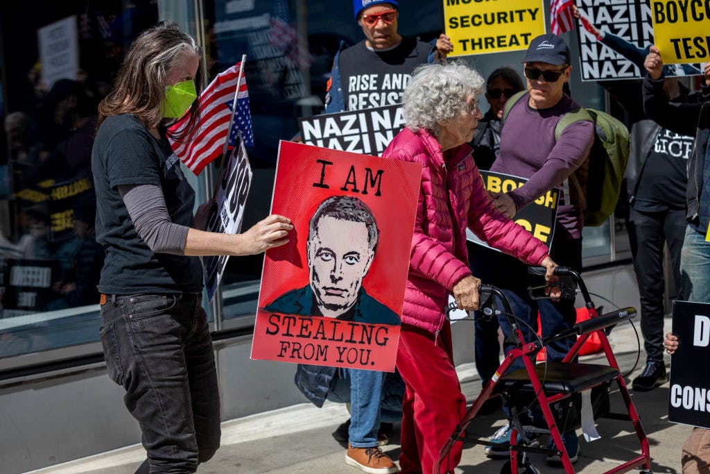 A person holds a sign that reads: "I am stealing from you"...