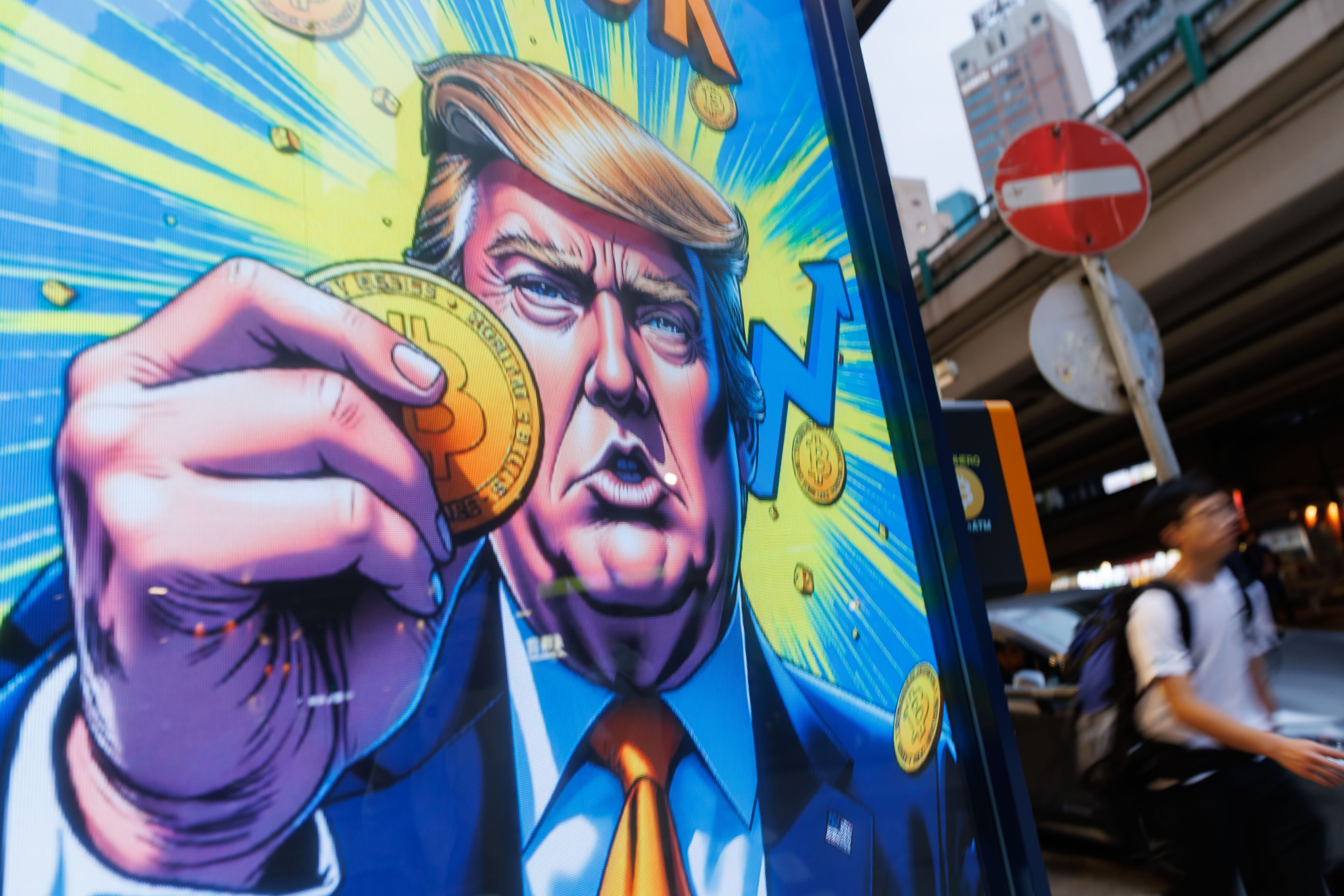 People walk past an advertisement feature Donald Trump with...