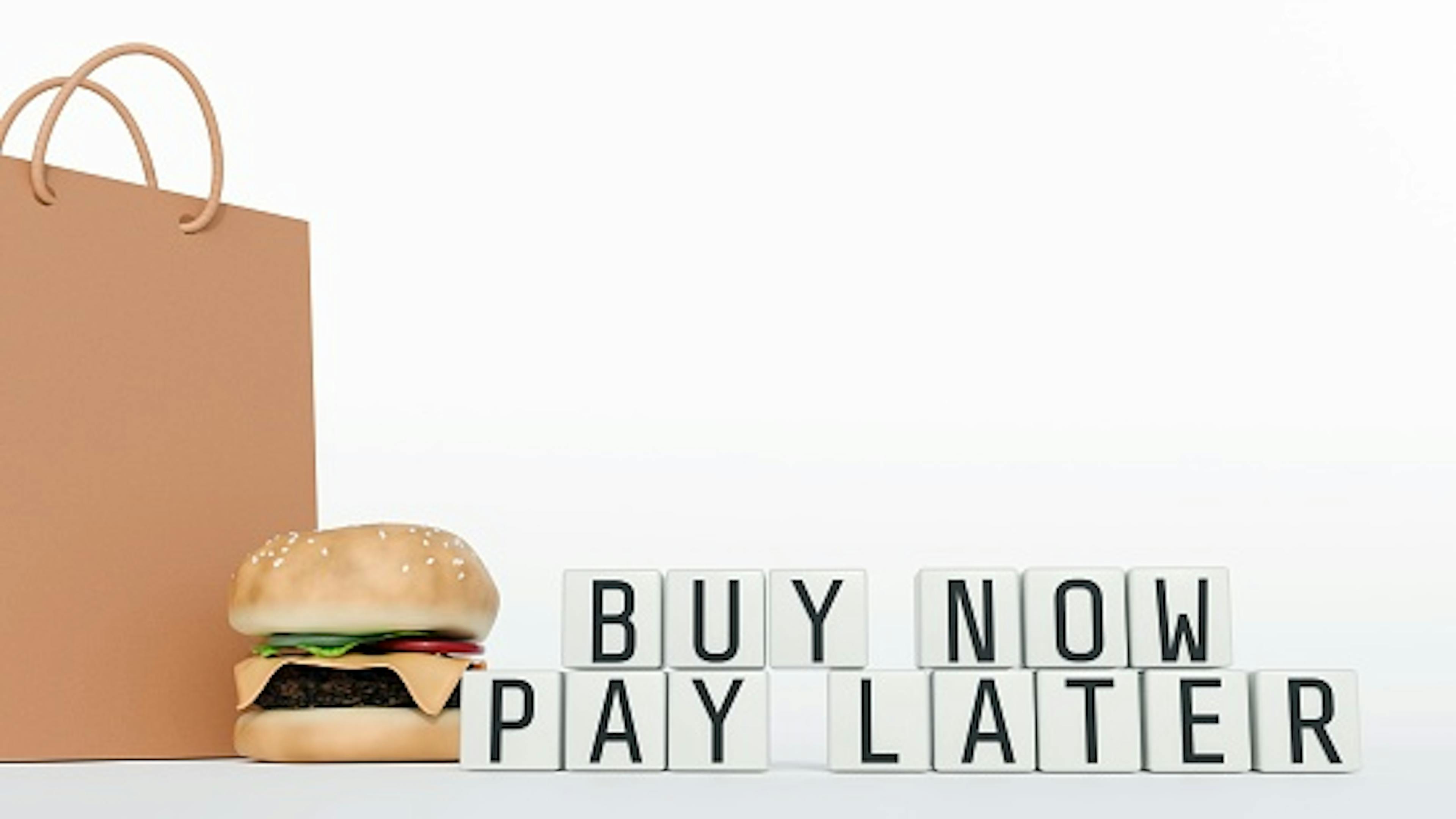 A 3d rendering of hamburger and white cube blocks with words "BUY PAY NOW LATER"