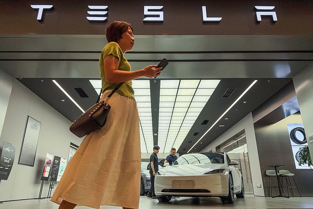 Woman Walks Past Tesla Showroom Featuring Display Vehicle in Chongqing