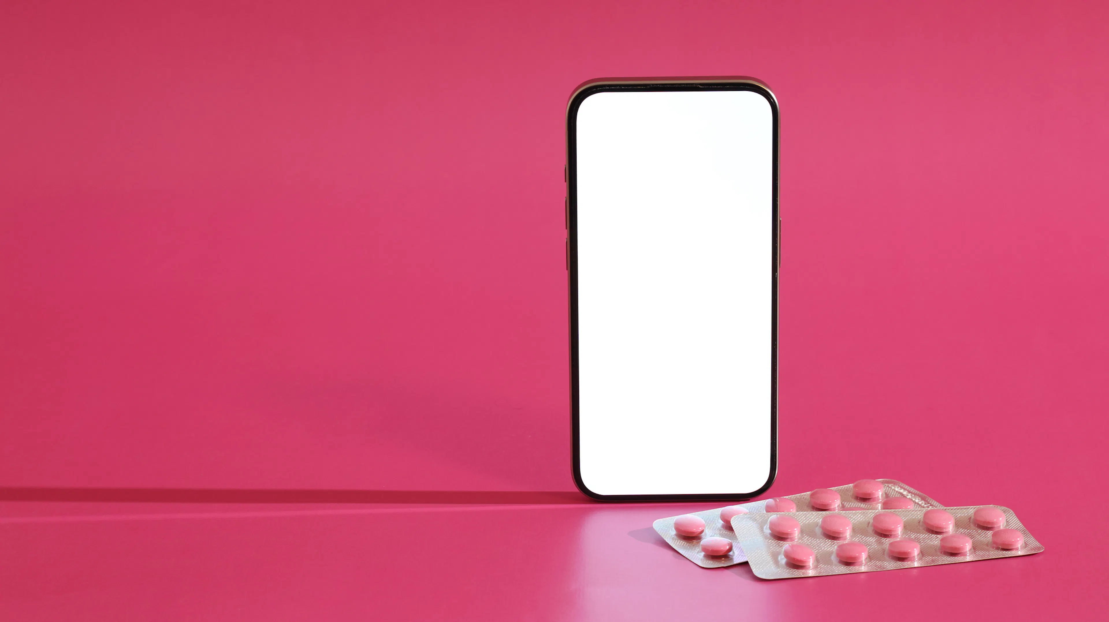 Women’s Health App on Smartphone with Pink Pills on Pink Background