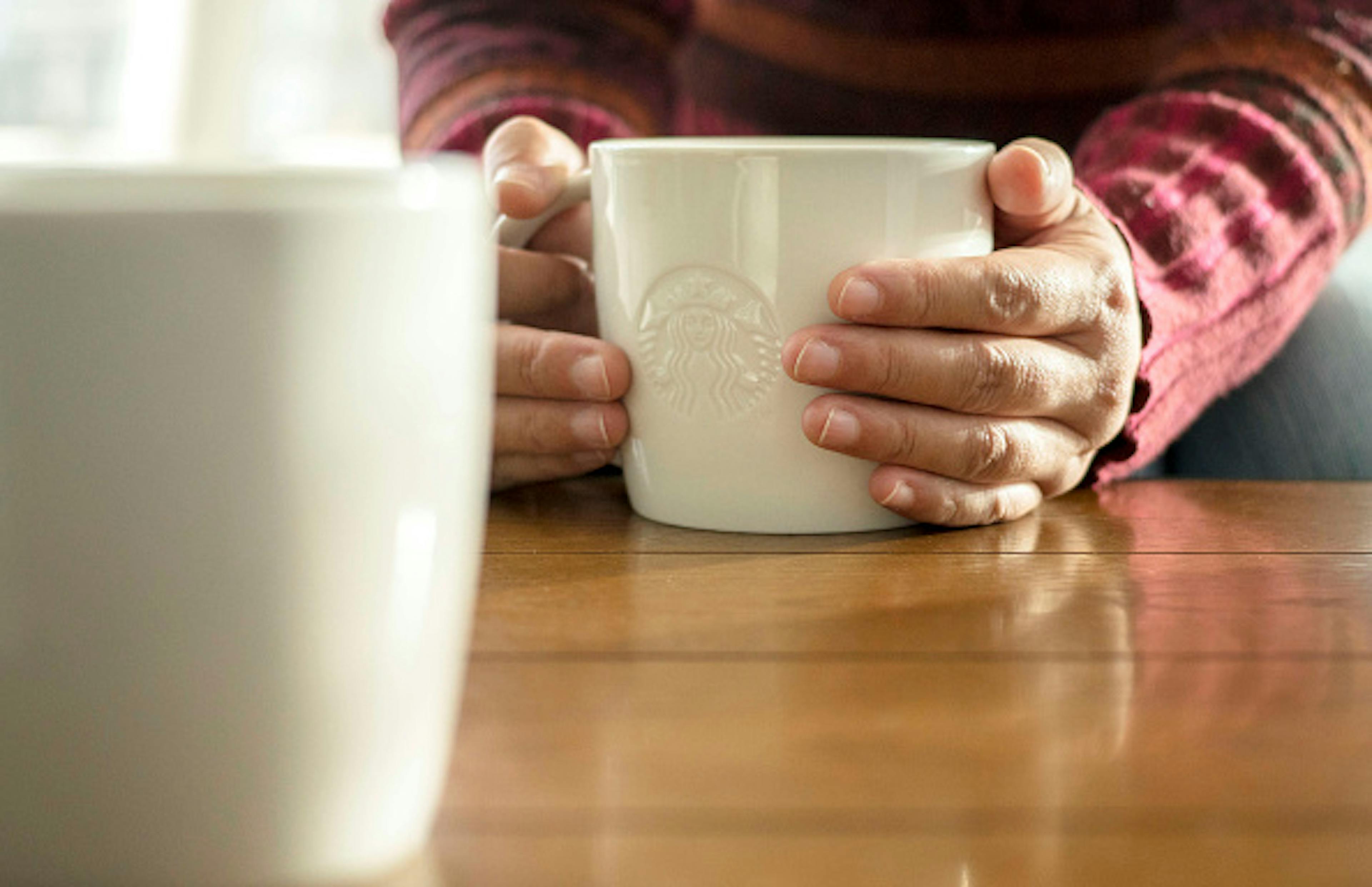 Customer holding a Starbucks coffee cup in hand