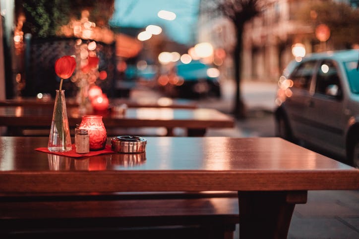 restaurant table with tulip, candle and ashtray with blurried street lights