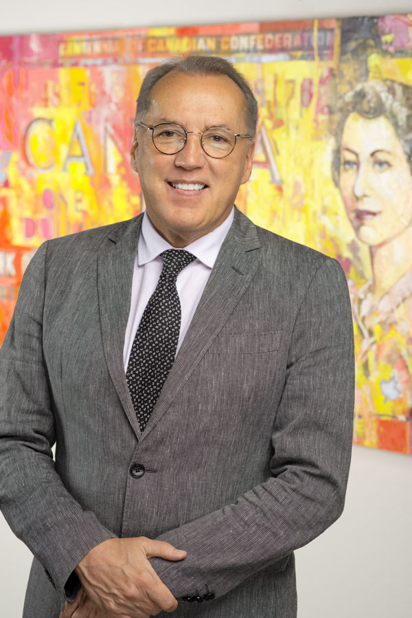 Frank Holmes smiling, wearing glasses and a gray suit