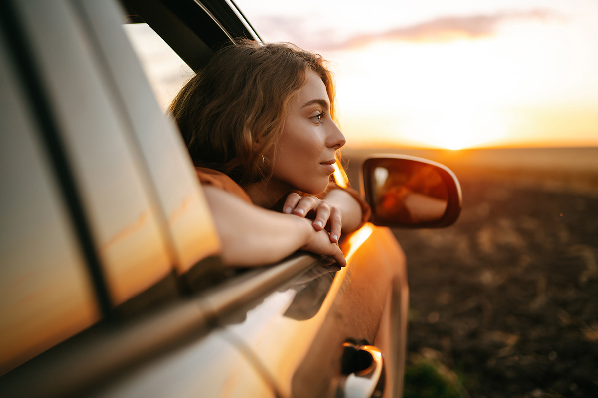Nasdaq Image: Woman staring out of car at sunset